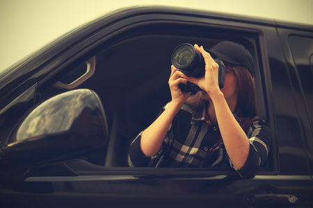 Private detective with camera spying from carの写真素材
