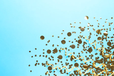 Shiny golden confetti and streamers on light blue background, flat layの写真素材