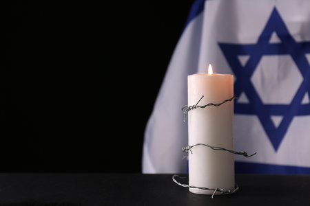 Barbed wire and burning candle on black background, space for text.の写真素材