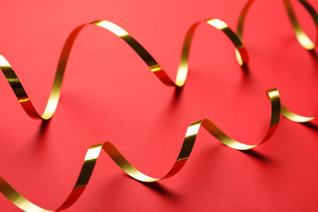 Shiny golden serpentine streamers on red background, closeupの写真素材