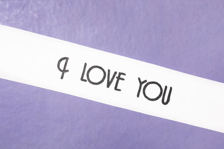Card with text I Love You on purple leather background, top viewの写真素材