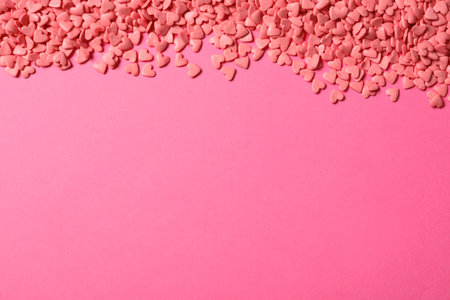 Heart shaped sprinkles on pink background, flat lay. Space for textの写真素材