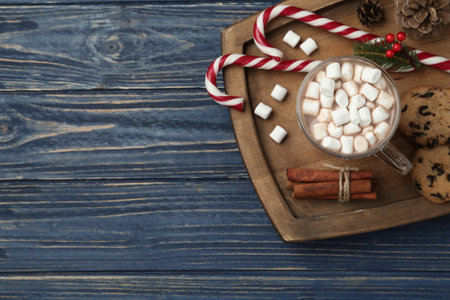 Hot drink with marshmallows and sweets on blue wooden table, top view. Space for textの写真素材