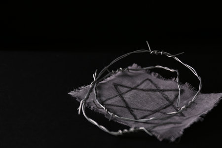 Fabric with star of David and barbed wire on black background, space for text.の写真素材