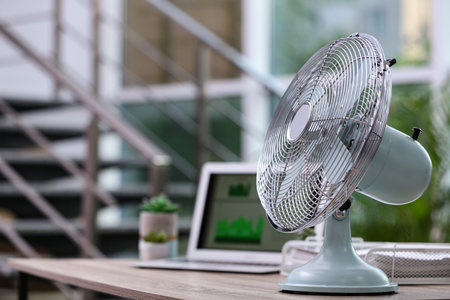 Modern electric fan on table in office. Space for textの写真素材