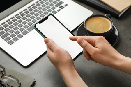 Woman using smartphone with blank screen at workplace, closeup