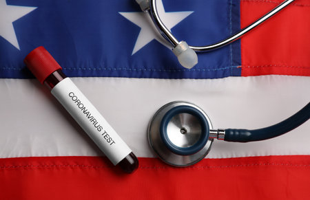 Test tube with blood sample and stethoscope on American flag, flat lay. Coronavirus pandemic in USAの写真素材