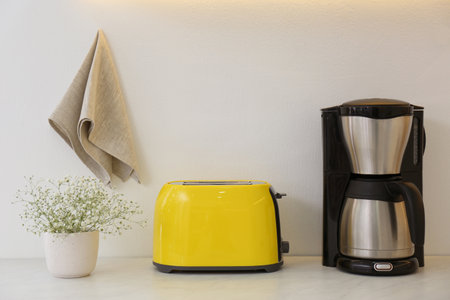 Modern toaster, coffee machine and flowers on counter in kitchenの写真素材