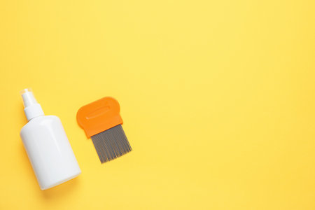 Spray and metal comb for anti lice treatment on yellow background, flat lay. Space for textの写真素材