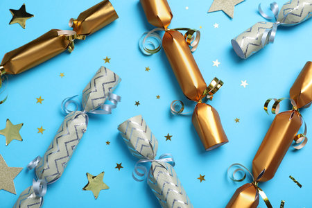 Christmas crackers and shiny confetti on light blue background, flat layの写真素材