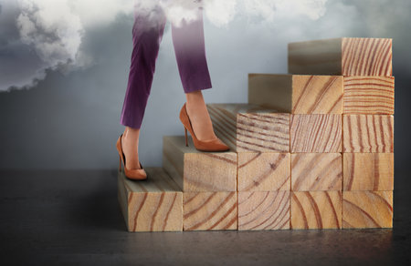 Businesswoman walking up stairs against grey background, closeup. Career ladder conceptの写真素材