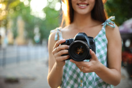 Young photographer with professional camera outdoors, closeupの写真素材