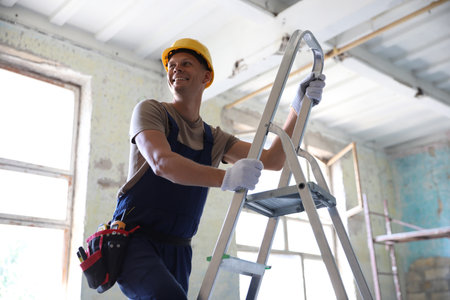 Professional constructor on ladder in old buildingの写真素材