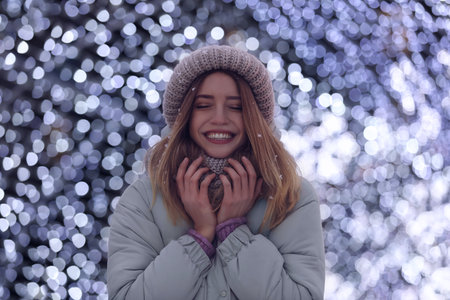 Happy young woman near festive lights in evening. Christmas celebrationの写真素材