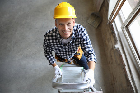 Professional constructor on ladder in old building, above viewの写真素材