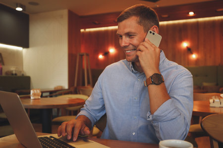 Happy man talking on smartphone in cafeの写真素材