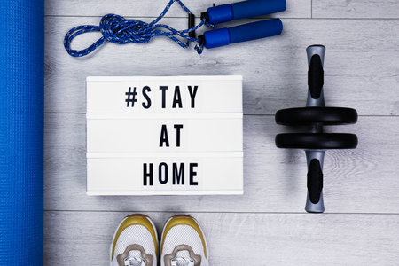 Sport equipment and lightbox with hashtag STAY AT HOME on floor, flat lay.の写真素材