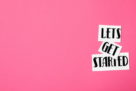 Sheets of paper with phrase Let's Get Started on pink background, flat lay. Space for textの写真素材