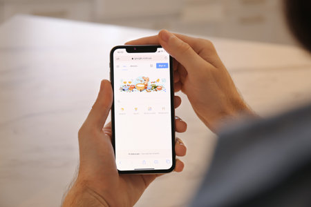 MYKOLAIV, UKRAINE - OCTOBER 27, 2020: Man using Google search engine on smartphone against blurred background, closeupのeditorial素材