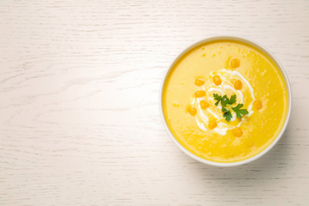 Delicious creamy corn soup served on white wooden table, top view. Space for textの写真素材