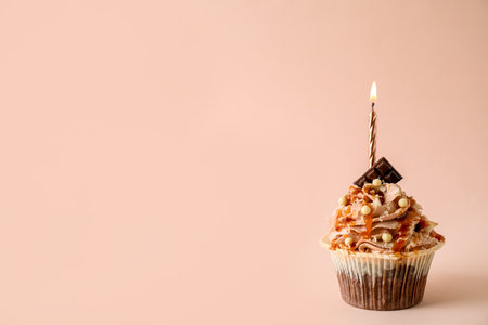 Delicious birthday cupcake with burning candle on pink background, space for textの写真素材