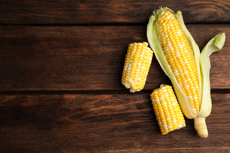 Tasty sweet corn cobs on wooden table, flat lay. Space for textの写真素材
