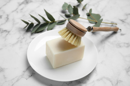 Cleaning brush and soap bar for dish washing on white marble tableの写真素材