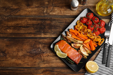 Tasty cooked salmon and vegetables served on wooden table, flat lay with space for text. Healthy meals from air fryerの写真素材