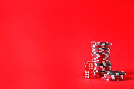 Poker chips and dice on red background, space for textの写真素材