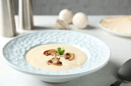 Delicious cream soup with mushrooms on white tableの写真素材