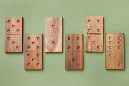 Wooden domino tiles on green background, flat lay