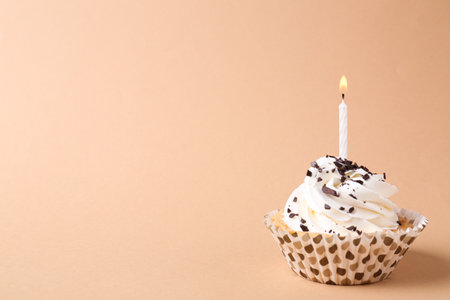 Delicious birthday cupcake with candle on beige background. Space for textの写真素材