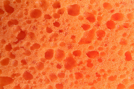 Clean orange sponge as background, top viewの写真素材