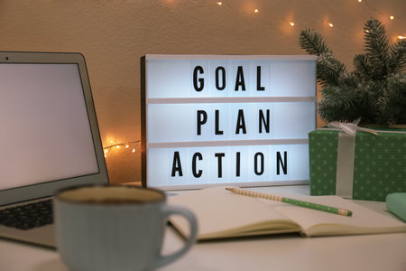 Light box with words Goal, Plan, Action near laptop and gift on tableの写真素材