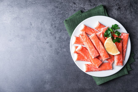 Fresh crab sticks with lemon on gray table, top view. Space for textの写真素材