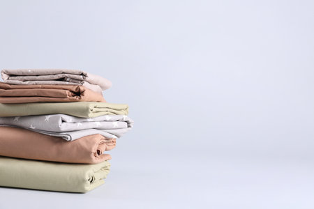 Stack of clean bed sheets on white background. Space for textの写真素材