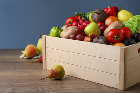 Crate full of different vegetables and fruits on wooden table, closeup. Harvesting timeの写真素材