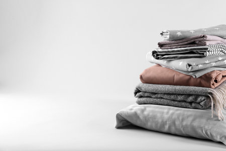 Stack of clean bed sheets and pillow on white background. Space for textの写真素材