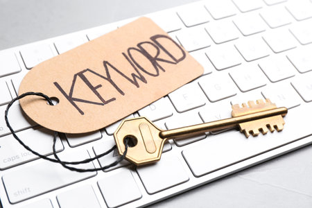 Key with tag KEYWORD and computer keyboard on table, closeupの写真素材