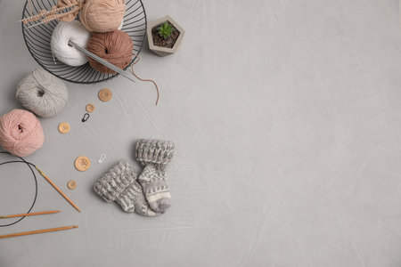 Flat lay composition with threads and knitted mittens on gray background, space for text. Engaging hobbyの写真素材