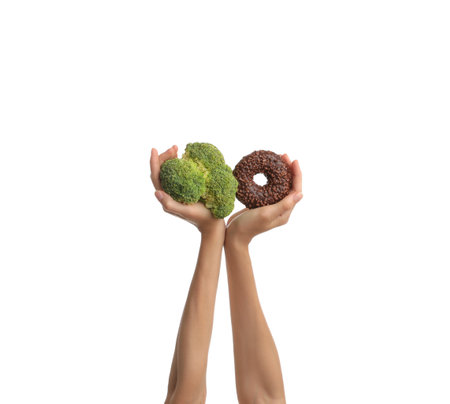 Woman choosing between donut and fresh broccoli on white background, closeupの写真素材