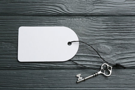 Key with blank tag on gray wooden table, top view. Keyword conceptの写真素材