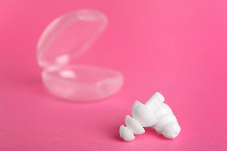 Pair of white ear plugs on pink background. Space for textの写真素材