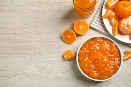 Flat lay composition with delicious tangerine jam on wooden table. Space for textの写真素材