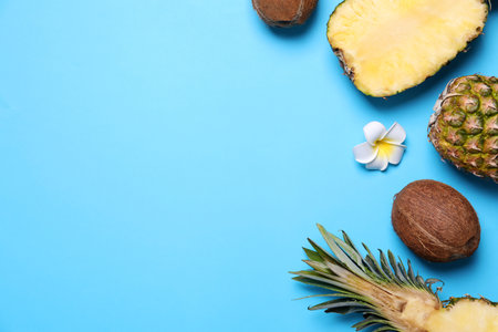 Flat lay composition with pineapples and coconuts on light blue background, space for textの写真素材