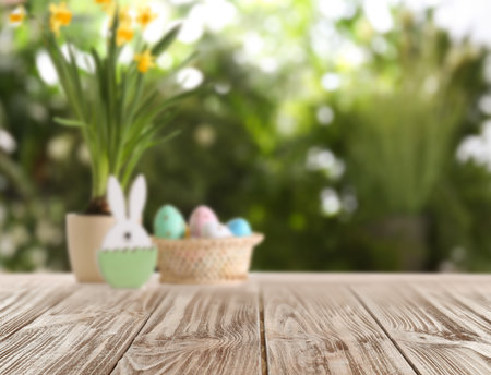 Empty wooden surface and wicker basket with colorful Easter eggs on backgroundの写真素材