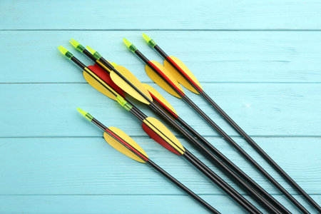Plastic arrows on turquoise wooden table, flat lay. Archery sports equipmentの写真素材