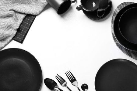 Frame made of black tableware on white background, flat lay. Space for textの写真素材