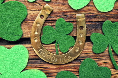 Decorative clover leaves and horseshoe on wooden background, flat lay. St. Patrick's Day celebrationの写真素材