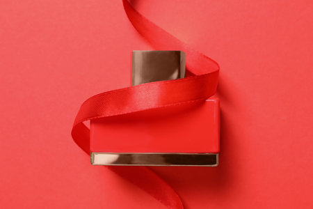 Bottle of perfume with ribbon on red background, top viewの写真素材